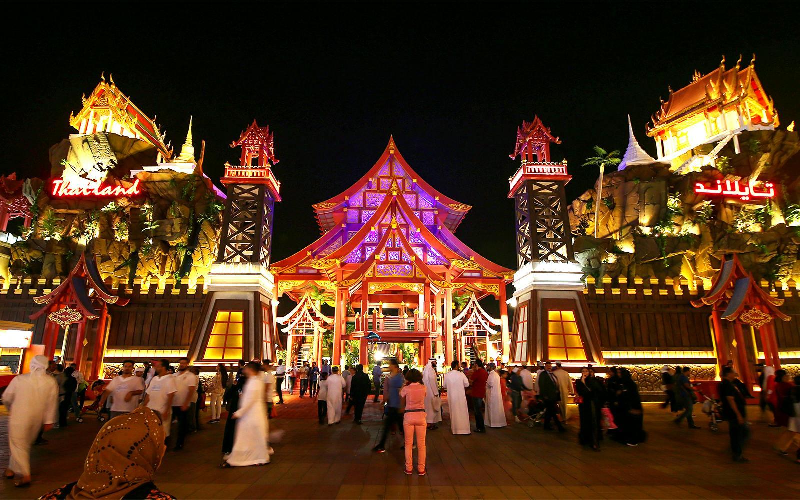 Tourists walking through the illuminated Thailand pavilion at Global Village Dubai.