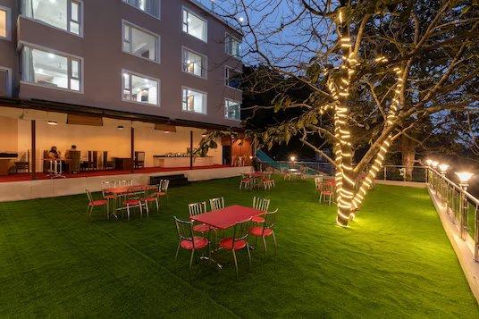 a garden area with tables and chairs at staybook hotel wild wood in mussoorie