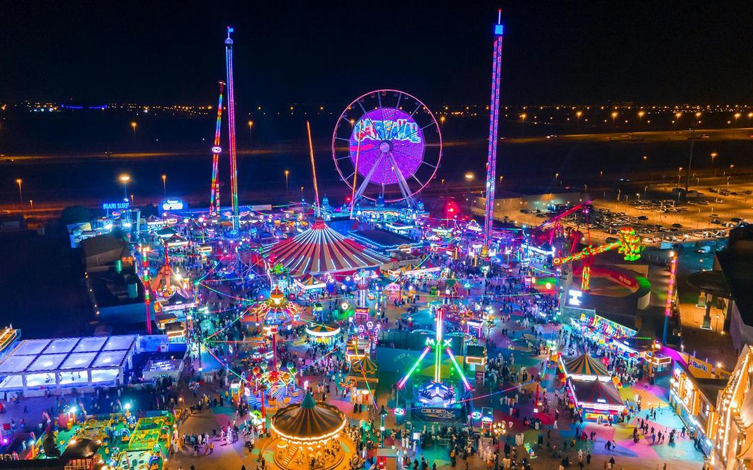 Aerial view of Global Village Dubai at night with colorful lights and Ferris wheel. Aerial view of Global Village Dubai at night with colorful lights and Ferris wheel.